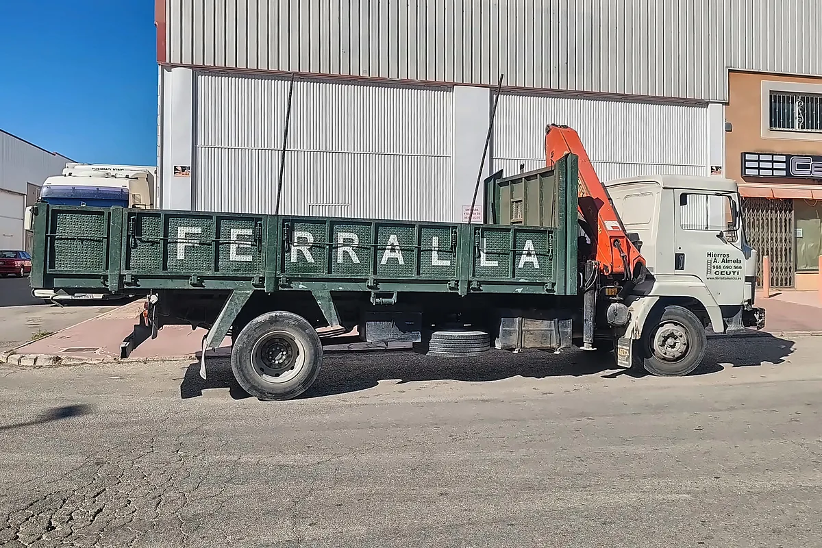 Camión grúa de Hierros Almela cargado, con la caja verde rotulada «FERRALLA».