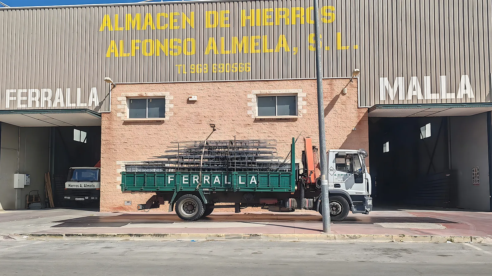 Fachada de Almacén de Hierros Alfonso Almela en Ceutí, con el camión grúa «FERRALLA» de la empresa delante.